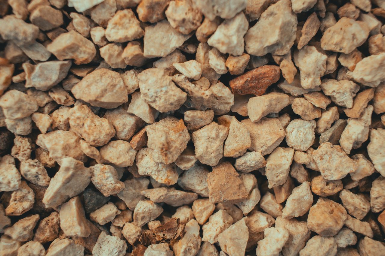 Detailed close-up of a rough brown pebble and stone surface showing texture and variety.